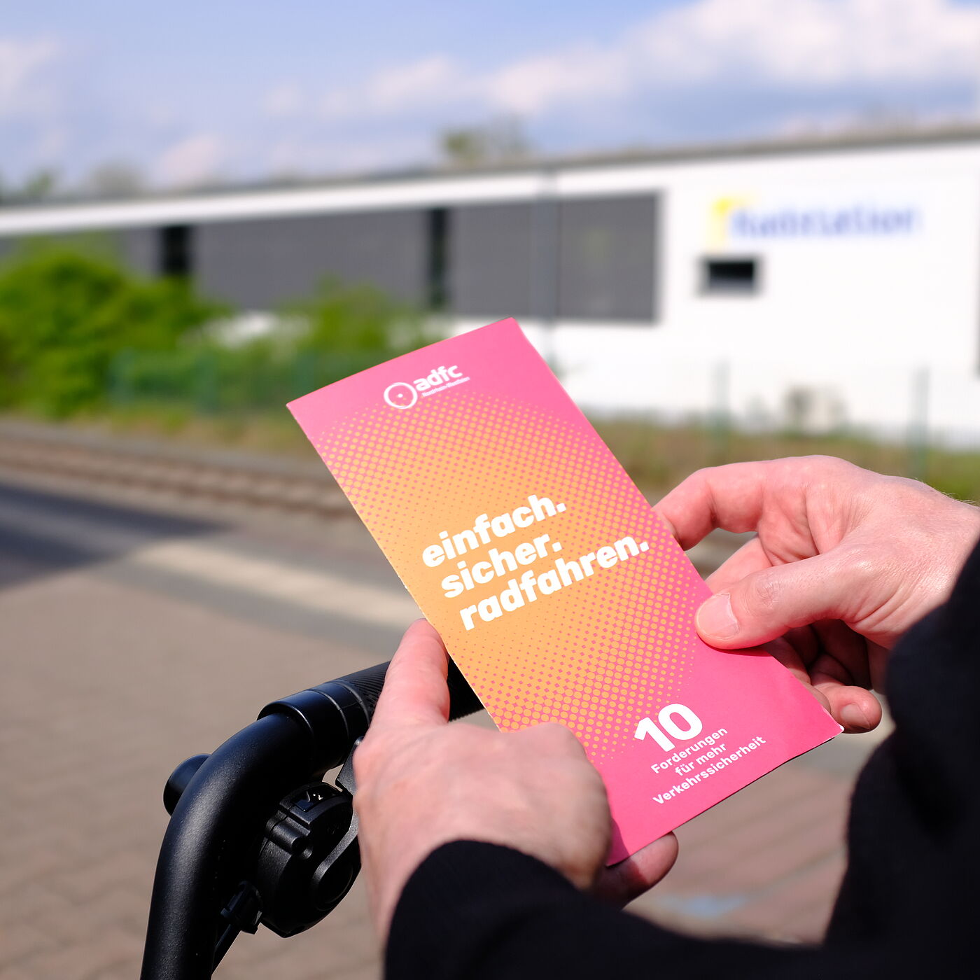 2026-04-17_Dormagen_Verkehrssicherheit__ADFC_NRW Eine Person hält einen Flyer in den Händen.