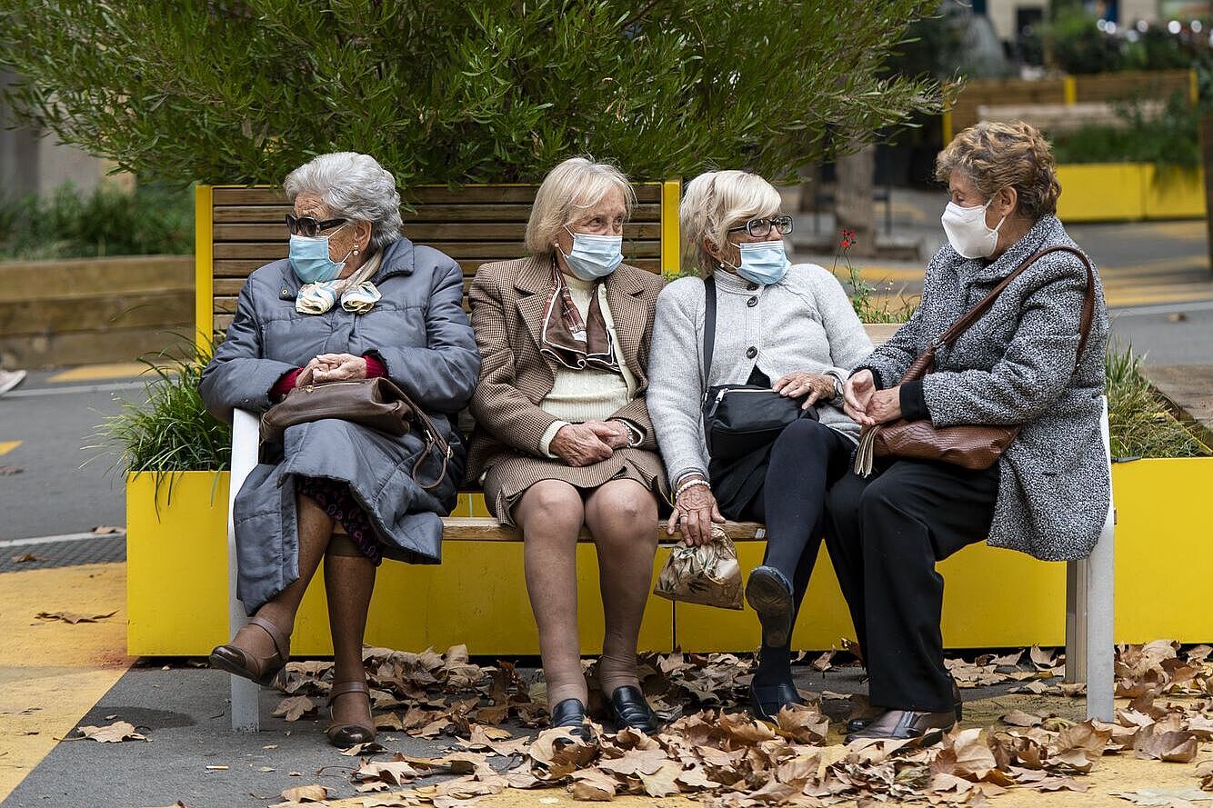 Vier Senior*innen sitzen auf einer Bank auf einer ehemaligen Straßenkreuzung. 