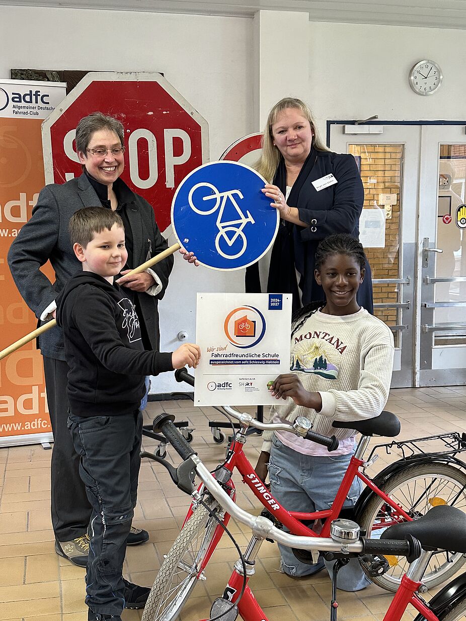 Stephanie Meyer (l.), Landesvorsitzende ADFC SH, und Schulleiterin Birgit von Glahn (r.) mit Schüler*innen Stephanie Meyer (l.), Landesvorsitzende ADFC SH, übergibt Plakette an Schulleiterin Birgit von Glahn (r.)
