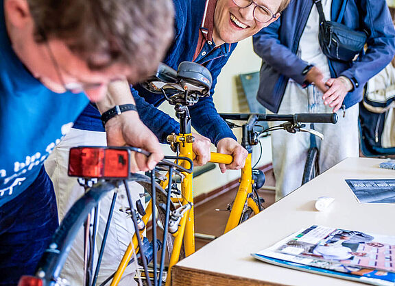 Jugendliche reparieren gemeinsam ein gelbes Fahrrad