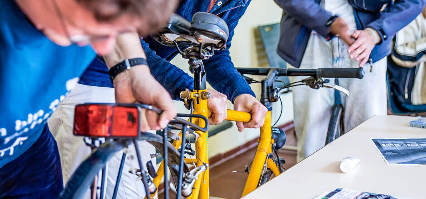 Jugendliche reparieren gemeinsam ein gelbes Fahrrad